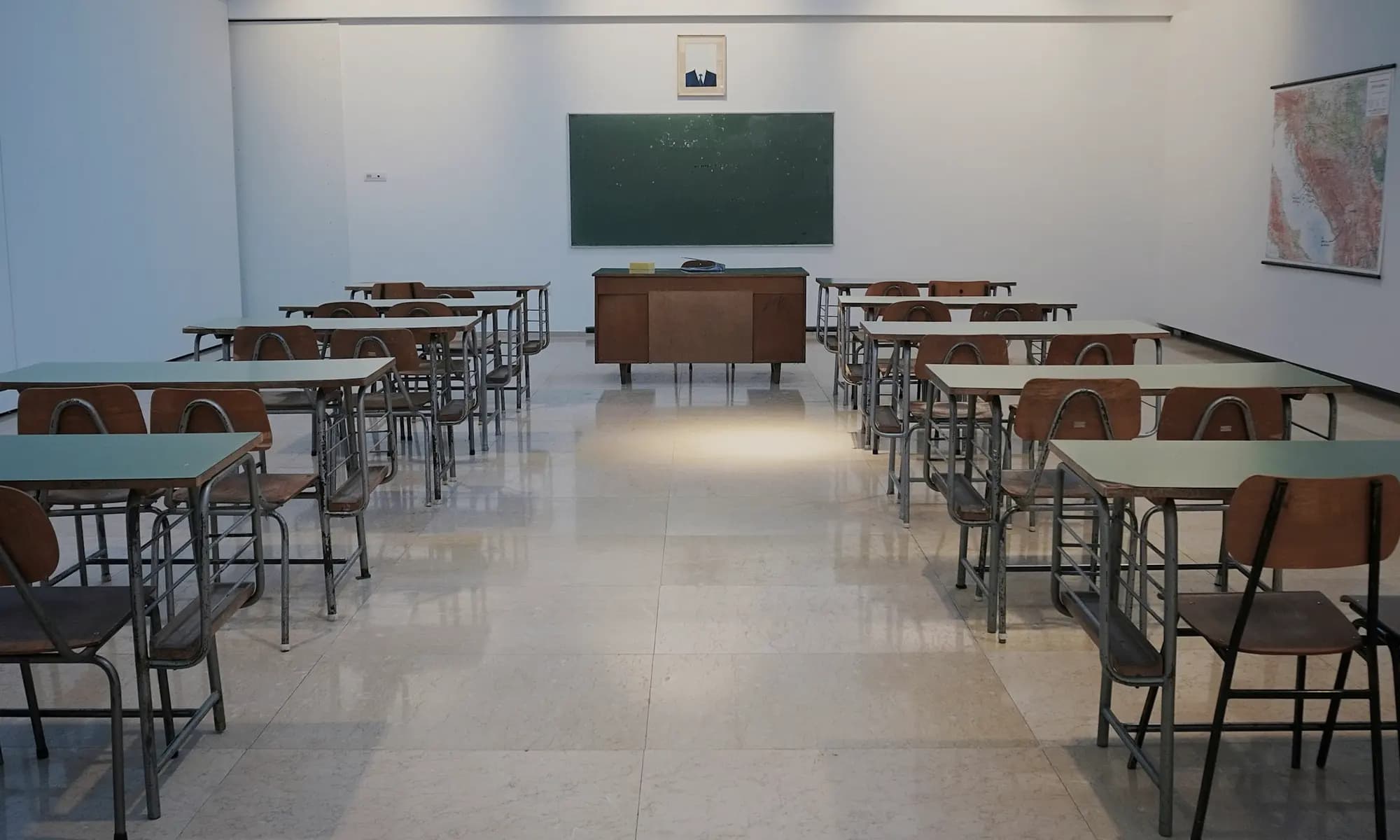 An empty classroom with wooden desks. Photograph by Ivan Aleksic on Unsplash. It is not a campus in this extract.